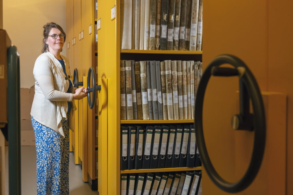 Een vrouw draaiend aan een wiel van een gele stellingkast.
