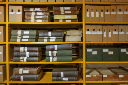Gele stellingkasten met links boeken en rechts dozen en daaronder kaartenbakken.
