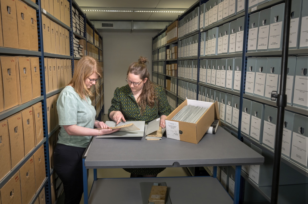 Een foto van het depot van Harderwijk. Op de voorgrond twee dames die archiefstukken inzien. Fotograaf Ruben Schipper