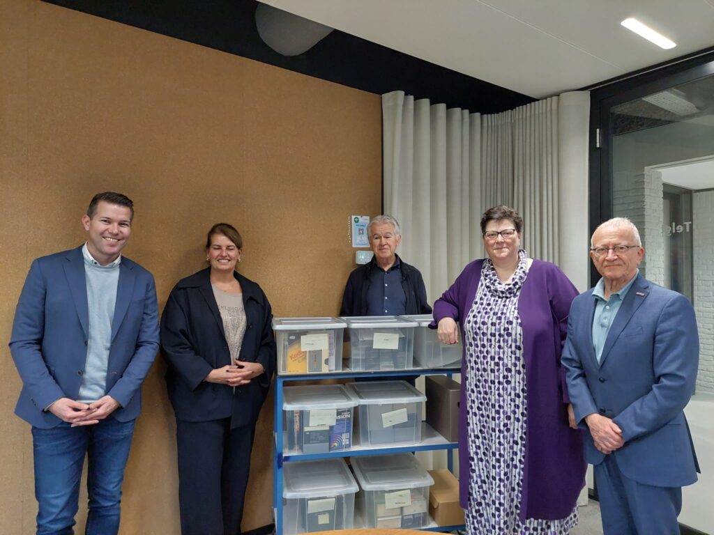 Rudolf Bosch (NoVA), Heidi de Bruin, Aristien Egbertzen (VHE), Renske van der Weij (NoVA) en Alex Kleijnen (VHE) poseren bij een deel van de collectie Willem de Bruin. Op de kar staan plastic bakken met videobanden.