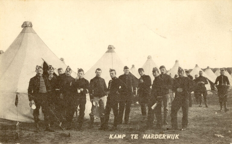 Op de Voorgrond een aantal mannen in uniform. Achter hun staan een aantal tenten. Als titel heeft deze prentbriefkaart Kamp te Harderwijk.