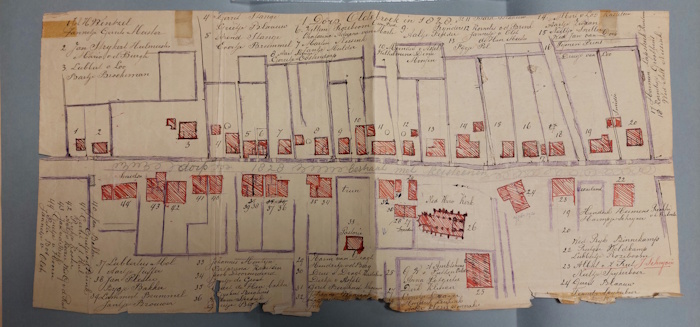 Een stuk papier met tekst en rode vakjes in grotere vakken. Dit gaat over staten van huisnummers. Plattegrond Oldebroek centrum