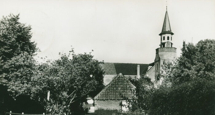 Een zwart wit foto van aan de rechterkant een kerk uit Nunspeet. Op de voorgrond staan bomen.