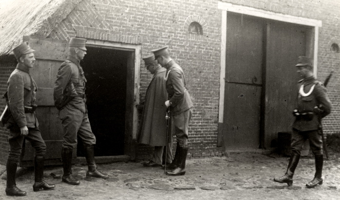 Zwart/wit foto van 5 mannen in uniform voor een boerderij.